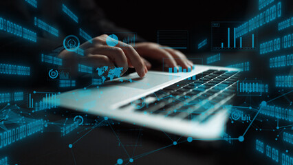 A close-up view of hands typing on a laptop, with floating digital data elements surrounding the device. The image represents modern technology and cyber analysis. Xenic