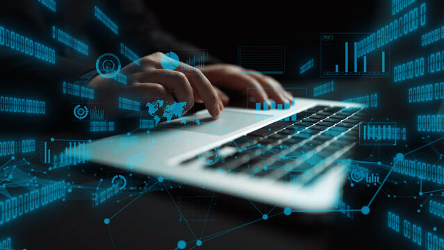 A close-up view of hands typing on a laptop, with floating digital data elements surrounding the device. The image represents modern technology and cyber analysis. Xenic