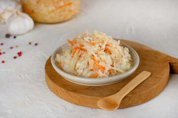 Fresh sauerkraut, pickled cabbage with carrot, pepper and garlic on a wooden board. Probiotic food.