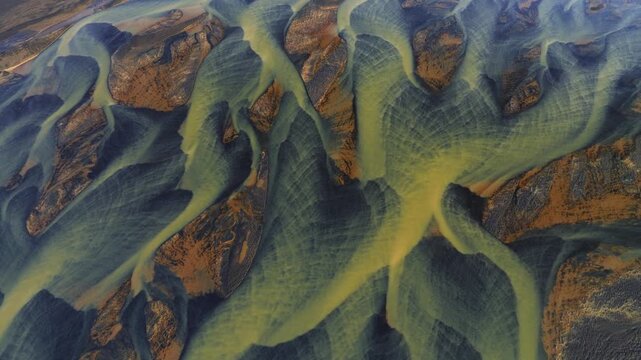 Aerial view of a river delta, showing the braided waterways and sediment deposits, with contrasting colors of blue and yellow, Grindavikurbaer, Iceland.