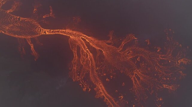 Aerial view of fiery orange lava snaking through the dark landscape creating a stark contrast of textures and tones, Reykjanes, Grindavikurbaer, Iceland.