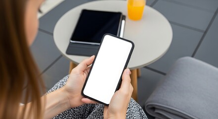 Woman holding smartphone with blank screen near tablet and juice on table outdoors showcasing mobile technology and connectivity in a relaxed setting