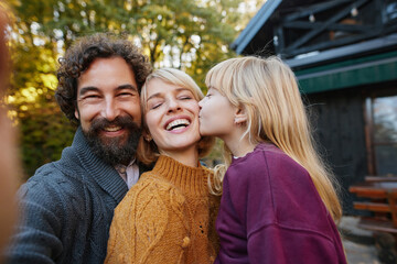 A family poses together in a vibrant autumn setting, sharing joyful smiles and affection. The warmth of the moment reflects their close bond during a relaxing weekend.