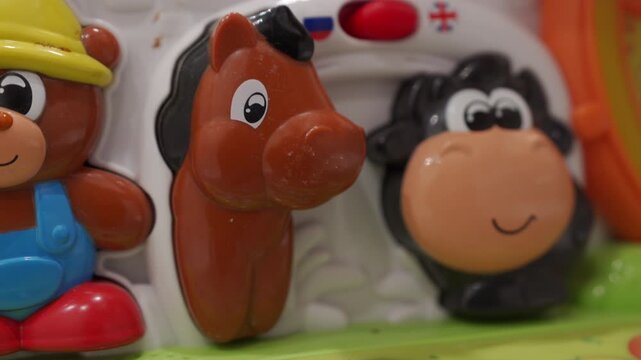 The brown horse button on a colorful plastic children's farm toy is pressed. This action triggers a voice that says "brown horse," immediately followed by a realistic horse neighing sound effect.