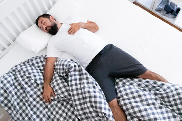 Relaxed young caucasian male sleeping comfortably on bed in casual attire