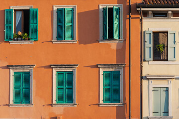 Close-up of the facade of a historic building in Verona, Italy, featuring several windows with shutters.