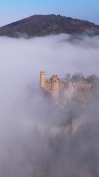 Aerial view of the medieval castle Auerbach ruins emerging through the misty fog, creating a mysterious and enchanting scene, Bensheim, Hessen, Germany.