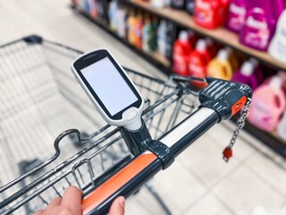 A hand-held bar code scanner on a shopping cart in a large supermarket. Modern Shopping Cart with Digital Display for Enhanced Grocery Shopping Experience and Efficient Product Selection