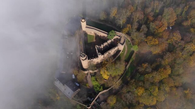 Aerial view of Castle Auerbach ruins amidst the autumn forest and shrouded in mist, creating an ethereal scene, Bensheim, Hessen, Germany.