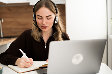 Hotline Operator. Woman in headset Consulting Clients in the kitchen at home office