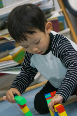 A focused child engrossed in playing with colorful blocks, a scene of creative building and developmental activity