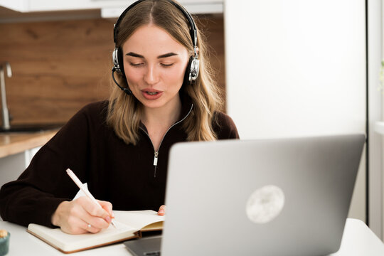 Hotline Operator. Woman in headset Consulting Clients in the kitchen at home office - Powered by Adobe