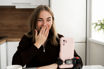 Portrait of shocked female student cover face scream wow omg in live stream online at home interior