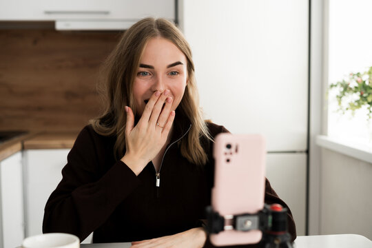 Portrait of shocked female student cover face scream wow omg in live stream online at home interior