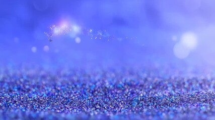 Close up of blue glitter particles and bokeh light creates an abstract sparkling surface ideal for festive designs, party invitations, product showcases, and celebration visuals