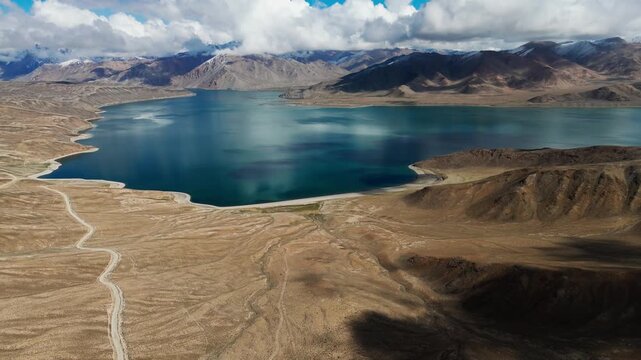 Aerial view of Yashilkul Lake near Bulunkul, Tajikistan, surrounded by highland mountains, reflecting serene waters and vast, pristine wilderness in Tajikistan