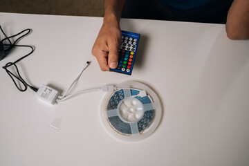 Skilled technician preparing RGB controller with led strip, configuring lighting setup for contemporary interior design with personalized illumination and smart home enhancement