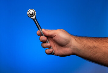 A man holding a torque wrench on a blue background. Men holding a torque wrench. Torque wrench tool