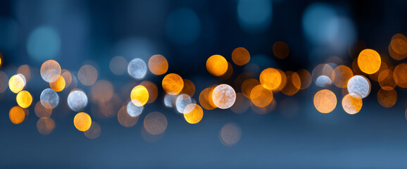 Abstract bokeh lights in warm orange and cool blue tones creating a blurred festive and dreamy background with circular light spots