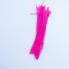 A bundle of bright  synthetic strands lies on a clean light background, showcasing fine texture, twisted filaments, and delicate details in a minimal composition.