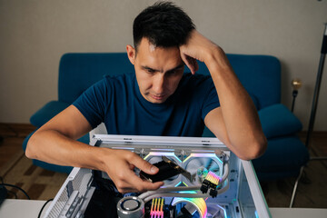 Portrait of puzzled technician upgrading desktop computer by installing wi-fi module, focusing intently on task with thoughtful expression, showcasing expertise and attention to detail at workshop.