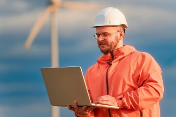 Engineer holding laptop outdoors with windmill