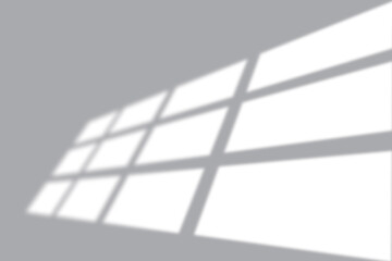 Modern window light casting geometric shadows on a neutral gray wall for a clean abstract background