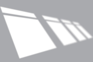 Soft window light creating geometric shadows on a clean, modern gray background for design.