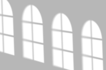 Soft sunlight patterns cast arched window shadows on a clean, minimalist wall creating a peaceful ambiance