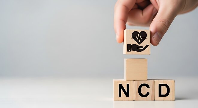 Hand stacking wooden blocks with ncd letters and heart symbol representing noncommunicable disease care