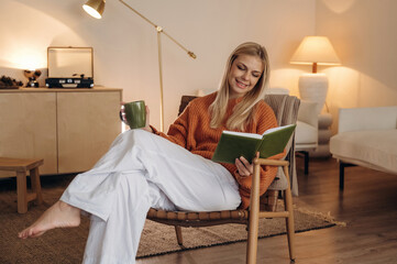 Obraz premium A woman is sitting on the chair in the room and reading the book