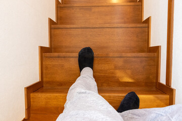 木製の階段を降りる人物の足元