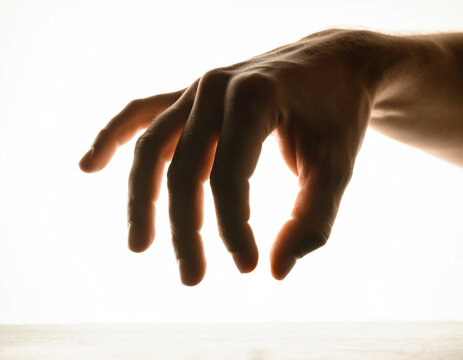 Hand reaching out to pick a snack from an invisible bowl, pinching gesture, macro shot, isolated on white background