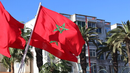 Waving Moroccan national flags with green pentagram against clear blue sky, fluttering red banners in Morocco, celebration background, national symbol, cultural identity