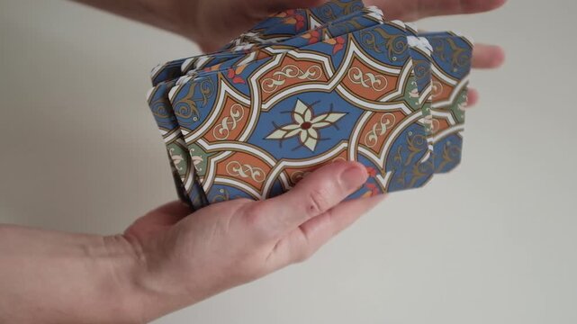 A female astrologer holding and tossing a deck of tarot cards in her hands. 