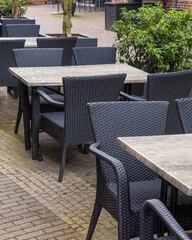 Empty black outdoor chairs and tables in front of a restaurant