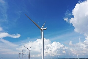Aerial view of powerful Wind turbine farm for energy production on beautiful cloudy sky at highland. Wind power turbines generating clean renewable energy for sustainable development green energy.
