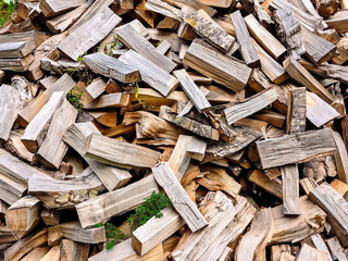 Close-up view of a pile of split firewood with rough bark, natural textures, and warm wooden tones. Detailed arrangement of chopped logs ready for burning. Rustic organic pattern.