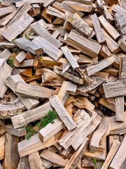 Close-up view of a pile of split firewood with rough bark, natural textures, and warm wooden tones. Detailed arrangement of chopped logs ready for burning. 