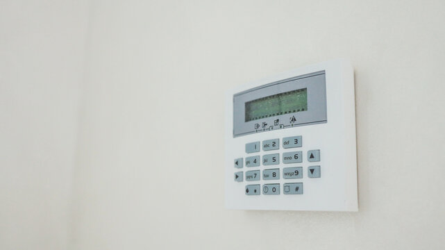 Security system keypad mounted on a white wall in a home or office setting