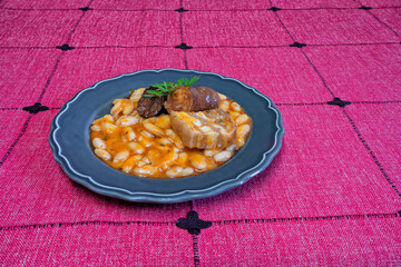 A plate of beans on a red tablecloth