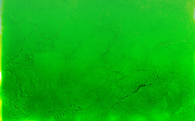 An aging green wall shows signs of wear with cracking and peeling paint, revealing the concrete beneath. The texture highlights the wall's deterioration and time's effect on the surface.