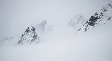 Serene snow-covered mountain peaks piercing through a misty sky. Ideal for travel, winter sports, adventure themes, and backgrounds, offering a peaceful, minimalist aesthetic.