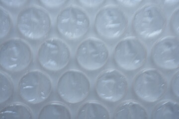 texture of white bubble wrap as a background. Transparent air-filled pockets create a structured, homogeneous pattern with a shiny, reflective surface. The bright pink colour accentua