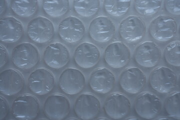 texture of white bubble wrap as a background. Transparent air-filled pockets create a structured, homogeneous pattern with a shiny, reflective surface. The bright pink colour accentua