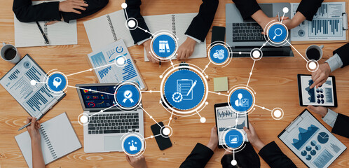Aerial view of a business meeting showcasing various digital devices, charts, and collaborative efforts among professionals focused on data analysis and strategic planning. Amity