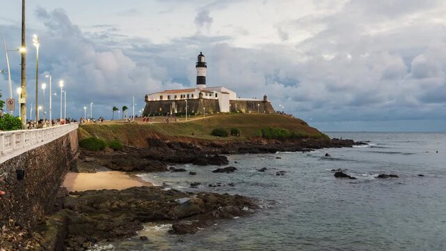 Day to night timelapse of the historic Farol da Barra, the oldest lighthouse in operation on the coast of Brazil and the Americas, in Salvador, Bahia, Brazil, zooming in.	
