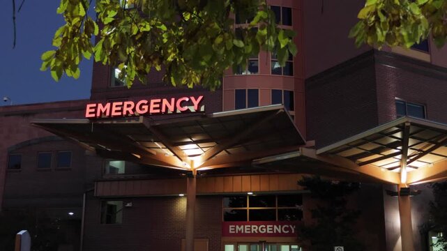 Hospital Emergency Room Entrance with Red Signage. Emergency Sign at Hospital in USA. Emergency Room and Medical Care Building. Hospital, Medical Center, Emergency Room. Evening Night Times.