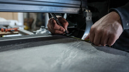 Craftsman measuring and marking a surface with a pencil and tape measure