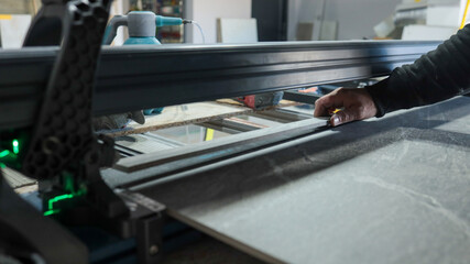 Man using a tile saw to cut a large ceramic tile in a workshop